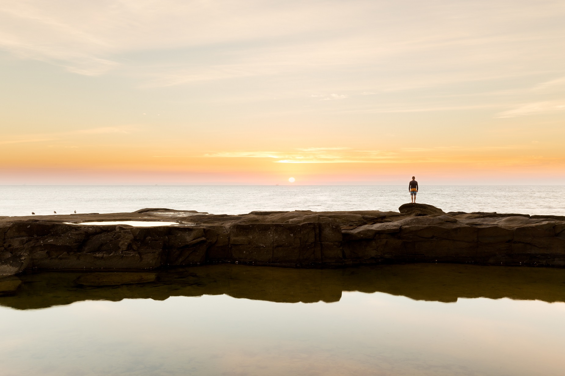 Homme face à la mer au lever du soleil